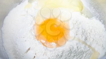 cooking of pie - pile of flour with broken egg close up in steel bowl