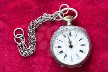 vintage silver pocket watch with chain on red velvet background