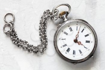 retro pocket watch with chain on light gray plaster background