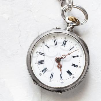 used silver pocket watch on light gray plaster background