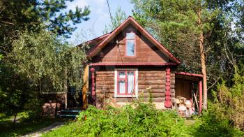 rural log house in green garden on sunny summer day in Tver region of Russia