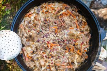 top view of cooking central asian dish plov in kazan pot on oven