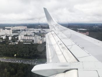 view of aircraft wing and Vnukovo district in Moscow suburb in Russia from the airplane porthole in flight in september evening