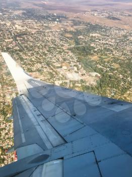 view of aircraft wing over Pyatigorsk city in Stavropol Krai of Russia from the airplane porthole in flight in september day