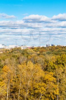 white clouds in blue sky over colorful forest of Timiryazevskiy park and residential district of Moscow city in sunny october day