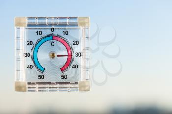 view of outdoor thermometer on home window and blue sky in hot twilight