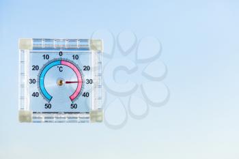 view of outdoor thermometer on home window and blue sky in hot morning