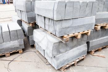 stockpiles of gray concrete curbs on street for road repairing