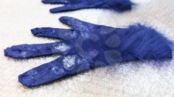 workshop of hand making a fleece gloves from blue Merino sheep wool using wet felting process - additional fibers close up on back side of glove with cutting pattern