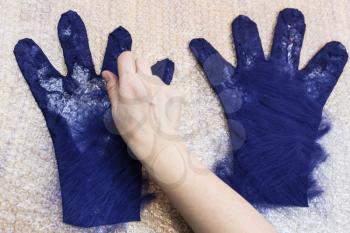 workshop of hand making a fleece gloves from blue Merino sheep wool using wet felting process- craftsman spreading fibers of back side of glove on the cutting pattern