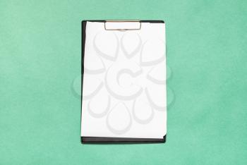top view of clipboard with blank white paper sheets on green background
