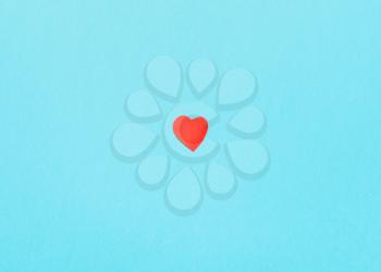 one little heart cut out of red paper on background from blue turquoise pastel paper