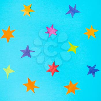 collage of various stars cut from colour papers on blue turquoise pastel paper
