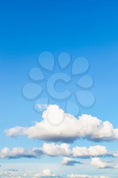natural vertical background - low white clouds in blue sky in summer evening