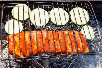 raw pork ribs marinated in sauce with sliced zucchini vegetable in outdoor grill
