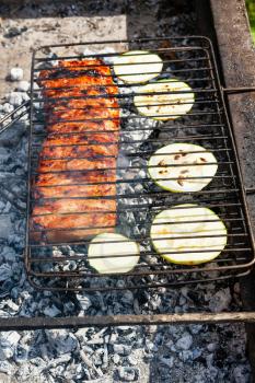 cooked pork ribs with sliced squash vegetable in outdoor charcoal grill