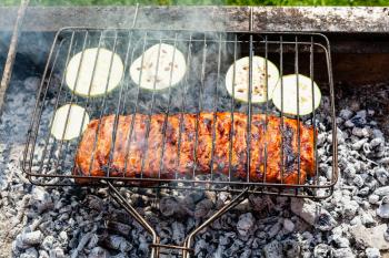cooked pork ribs with sliced zucchini vegetable in outdoor charcoal grill