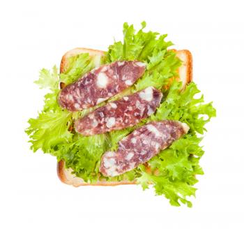 top view of open sandwich with toast and three slices of cured sausage and fresh green leaf lettuce isolated on white background