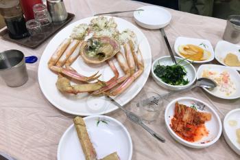 served crab on plate and various banchan (korean small dishes) in local cafe at Taepo Fish Market in Sokcho city, South Korea (snapshot by mobile smartphone)