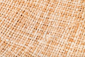textile background - weaving of summer straw hat from natural raffia fibers close up