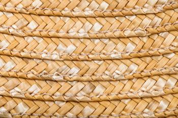textile square background - detail of stitched summer straw hat from raffia fibers close up