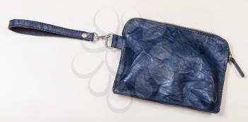 closed small blue leather wristlet purse bag on pale brown table