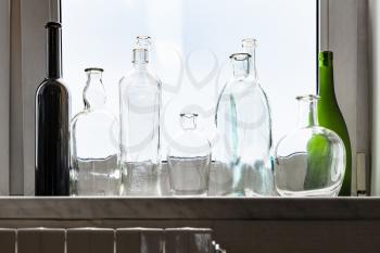 various empty drunk bottles on home windowsill on overcast day