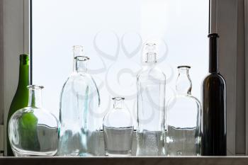 many empty drunk bottles on home window sill on overcast day