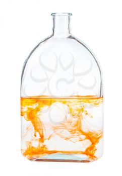 orange watercolour dissolving in water in glass flask isolated on white background