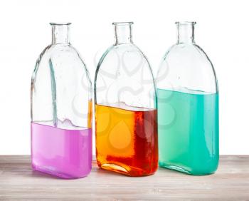glass bottles with color watercolour solutions on wooden board with cutout background