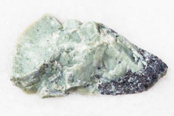 natural mineral from geological collection - raw Teisky Jade (Hantigyrite, khakassian serpentine) rock with Magnetite, Serpentine, Hematite minerals from Teyskoye mine, Khakassia on white marble