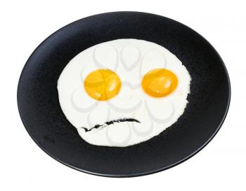 fried eggs on black plate isolated on white background. Fried eggs like the angry face