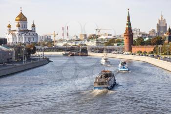 view of excursion boats in Moskva River and Kremlin tower, Cathedral of Christ the Saviour and skyscraper of Ministry of Foreign Affairs from Bolshoy Moskvoretsky Bridge on sunny autumn day