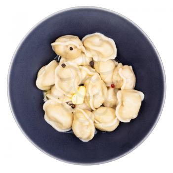top view of boiled Pelmeni (russian dumplings filled with minced meat) with butter and peppercorn in black bowl isolated on white background