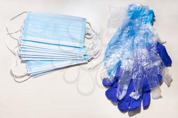above view of disposable protective face masks and hand gloves on light brown table