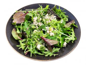 vegetarian salad from chard and arugula with blue cheese, pepper and olive oil on dark brown plate isolated on white background