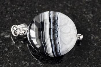 pendant from striped Agate gemstone on black granite background