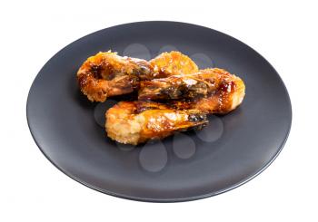 several fried tiger prawns on black plate isolated on white background
