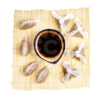 chinese cuisine - top view of various Dim sum and soy sauce in bowl on wooden mat isolated on white background