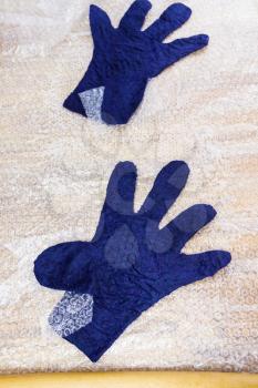 workshop of hand making a fleece gloves from blue Merino sheep wool using wet felting process - felted gloves after rolling and pressing