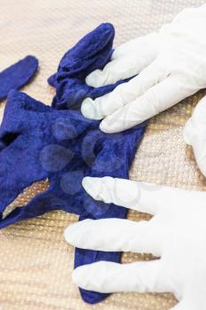 workshop of hand making a fleece gloves from blue Merino sheep wool using wet felting process - craftsman condensing the felted glove on mat