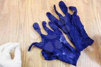 workshop of hand making a fleece gloves from blue Merino sheep wool using wet felting process - wet and crumpled felted gloves after fulling