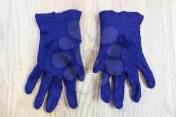 workshop of hand making a fleece gloves from blue Merino sheep wool using wet felting process - finished wet felted gloves on mat
