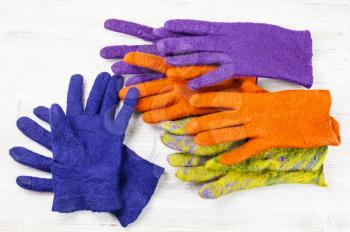 workshop of hand making a fleece gloves from sheep wool using wet felting process - multicolored woolen handmade felted gloves on wooden table