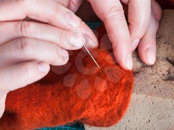 master class of repairing fleece glove using Needle felting process - craftsman mixes fibers in felt with felting needle close up