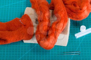 master class of repairing fleece glove using Needle felting process - above view of material and tools for felting on mat