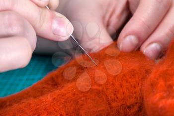 master class of repairing fleece glove using Needle felting process - craftsman poking felted cloth with felting needle close up
