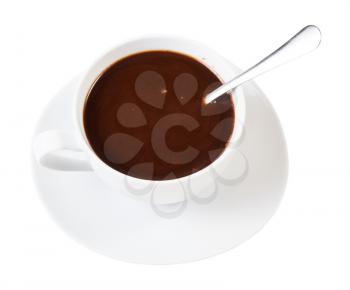 above view of hot carob powder drink in white porcelain cup with spoon on saucer isolated on white background