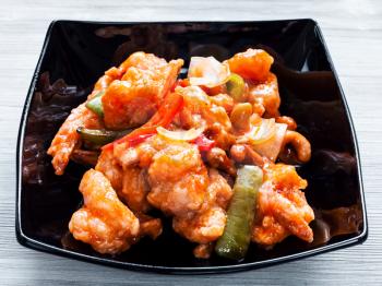 korean cuisine - stir-fried Shrimps with cashew nuts and vegetables in sweet and sour sauce (Shrimps Combo) in black bowl close up