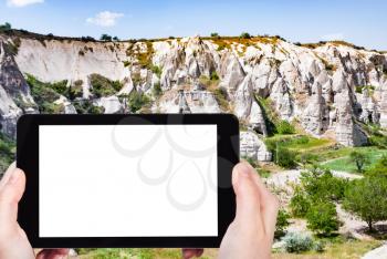 travel concept - tourist photographs of landscape with ancient cave churches near Goreme town in Cappadocia in spring in Turkey on smartphone with empty cutout screen with blank place for advertising